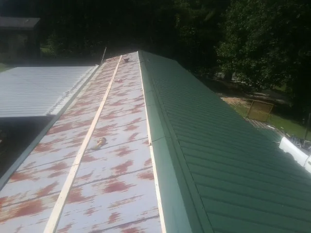 Old rusted panels beside newly installed green metal roofing — Wind Damage Roof Repair by Roofing Brothers in Lebec