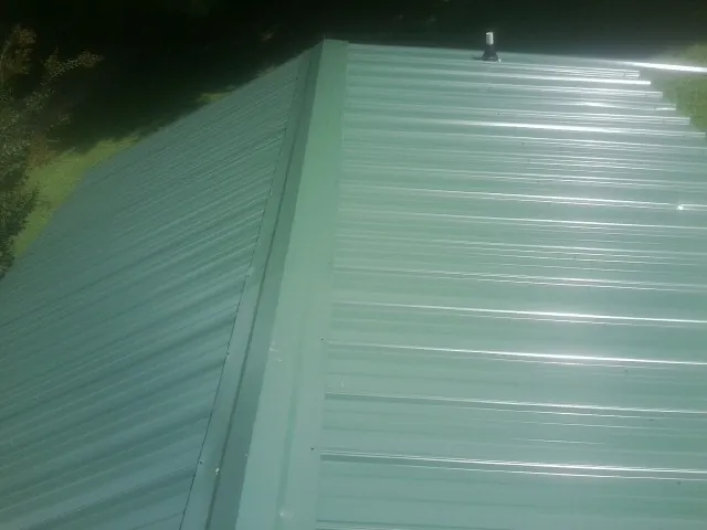 New green metal panels meeting at the ridge of a roof — Flat Roof Repair work by our crew in Lebec