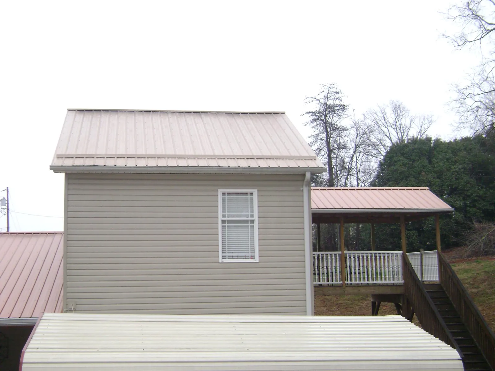 Tan metal roofs on a two story addition and attached porch, from a Roof Replacement job in Lebec